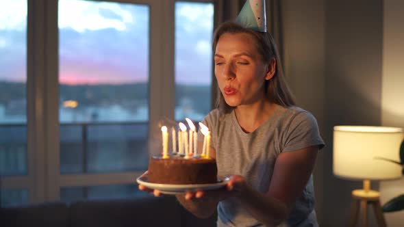 Happy Excited Woman Making Cherished Wish and Blowing Candles on Holiday Cake Celebrating Birthday