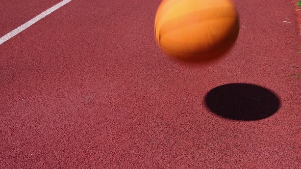 Dribbling basketball ball on red court