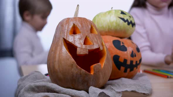 Smiling Halloween Pumpkins on the Table in the Room Blurry Boy and Girl in the Background