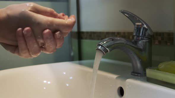 A Woman Washing Her Hands with Soap in the Bathroom To Eliminate Germs and Protect Against the Virus