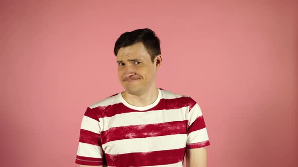 A Man in a Striped T-shirt on a Pink Background. Looking Camera Says No