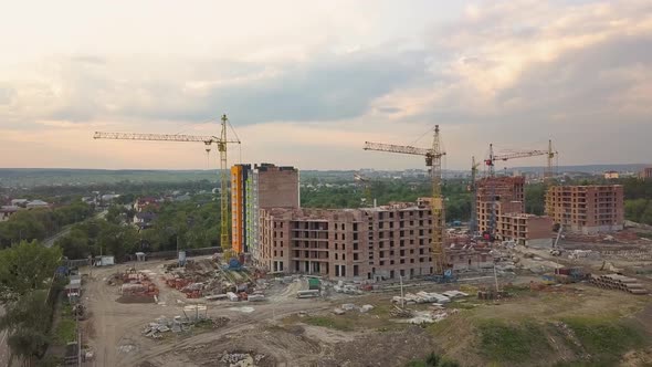 Aerial view of construction site with building cranes and high rise apartment buildings in a city.