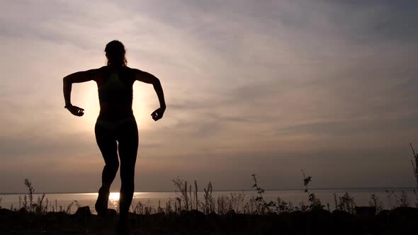 Silhouette of Fit Woman Enjoying Sunset on Shore