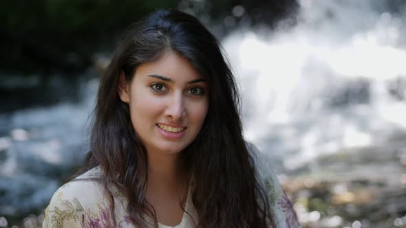 Smiling pretty brunette near the waterfall