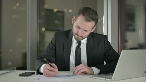 Young Businessman Working on Document in Office at Night