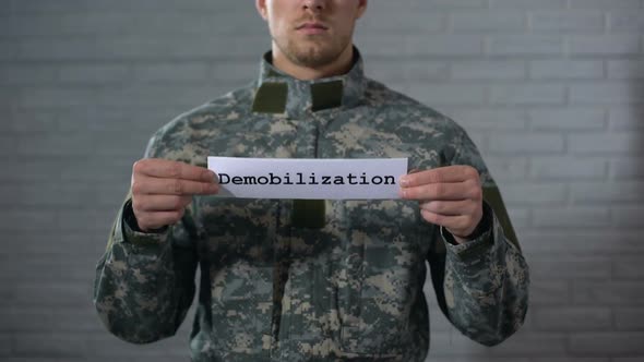 Demobilization Word Written on Sign in Hands of Male Soldier, End of Term