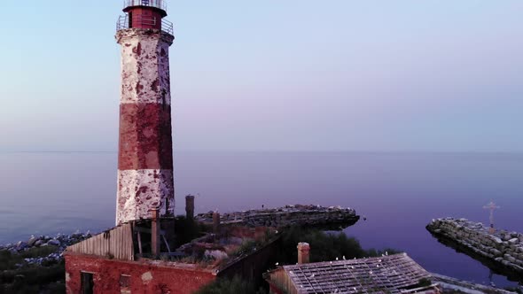 Cinematic aerial shot of small island with old lighthouse, camera fly back