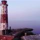 Cinematic aerial shot of small island with old lighthouse, camera fly back - VideoHive Item for Sale