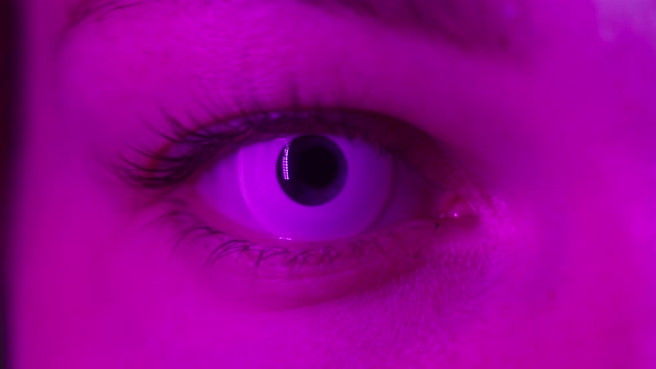 Closeup of Young Woman Eye Wearing White Decorative Lenses in Ultraviolet Light