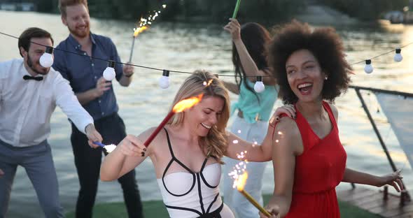 Friends Enjoying a Party and Dancing with Sparklers in Hands