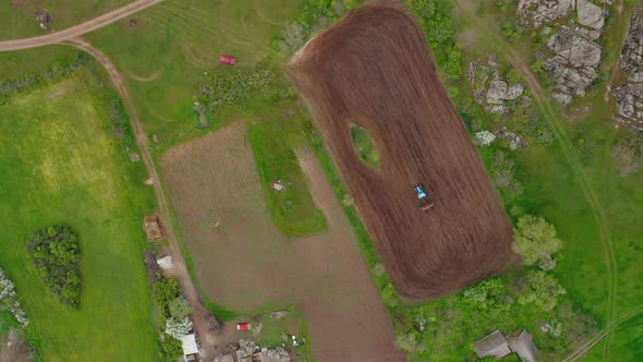 Aerial View of a Tractor Planting a Field on a Small Plot of Fertile Land