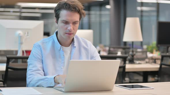 Man Celebrating Success While Using Laptop in Office