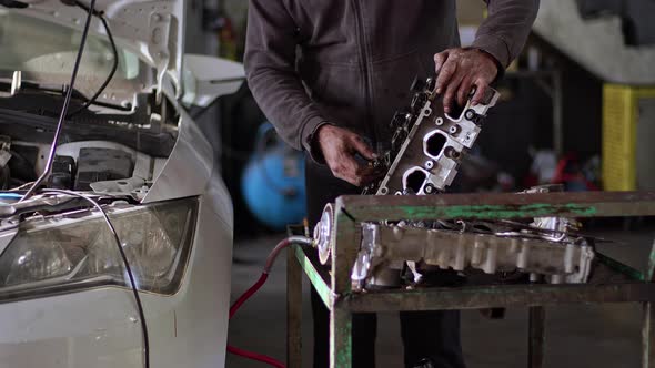 Car Master Repairing Cylinder Head Of Car Engine In Repair Shop