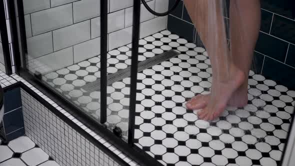 Woman Stands in Shower with Black and White Tiles