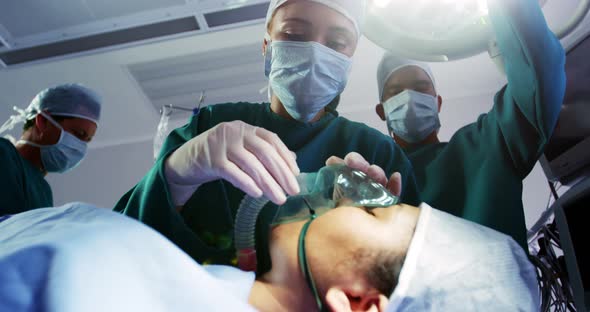 Surgeon putting oxygen mask on patient in operation room