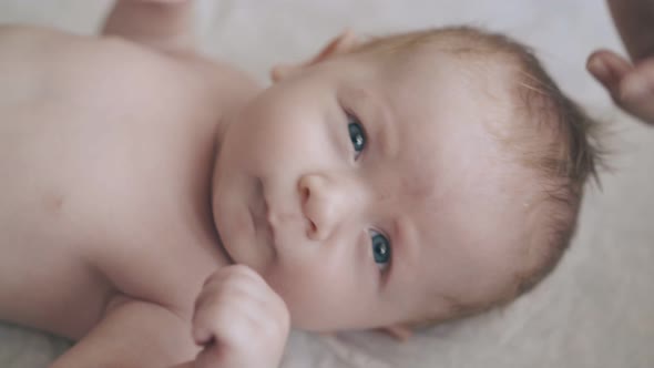 Newborn with Bright Blue Eyes Short Hair Looks at Camera