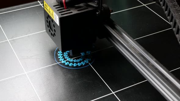 Electronic 3D printer during work. Blue plastic object is being printed in 3D