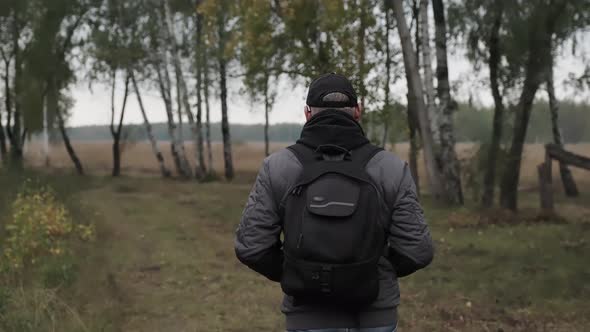 Male tourist walks through the birch grove