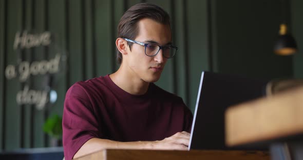 Handsome Young Man Using Laptop Sitting in Cafe