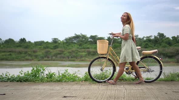 Young woman with bicycle walking on the park