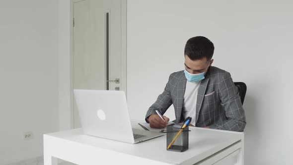 Male Student in Medical Mask Working with Laptop at Table During Remote Studying