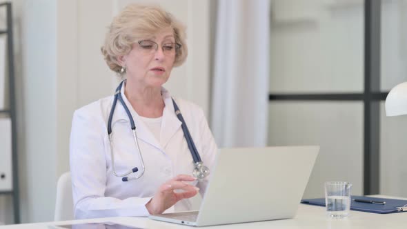 Old Female Doctor Talking on Video Call on Laptop