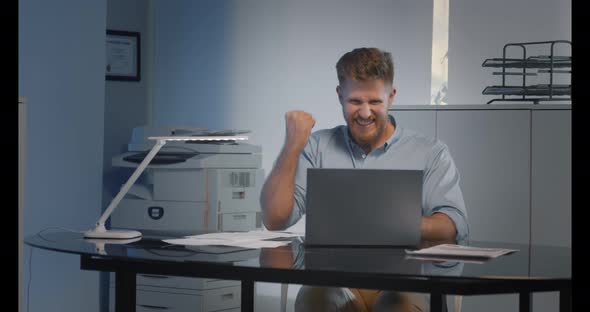 Happy Young Businessman in Shirt with Laptop Excited By Good News Online