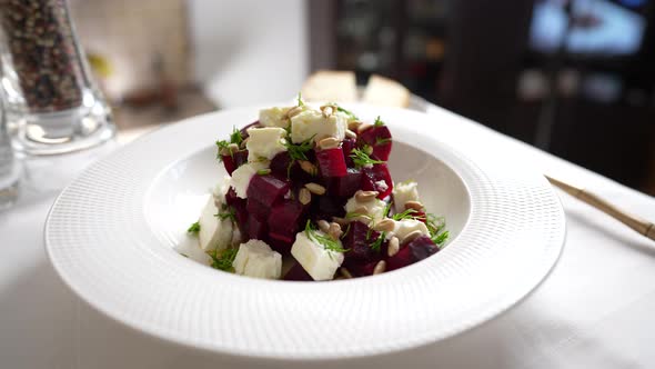 Salad with beetroot, feta cheese and sunflower seeds in white plate, rotates