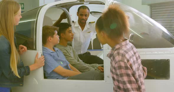 Male pilot explaining about aeroplane to kids 