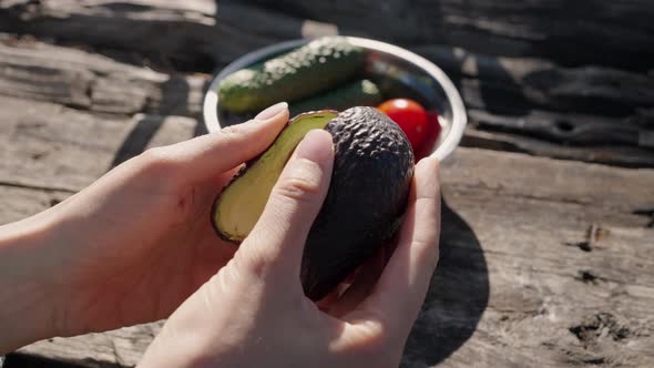 Person Hands Demonstrate Avocado Pieces on Sunny Day