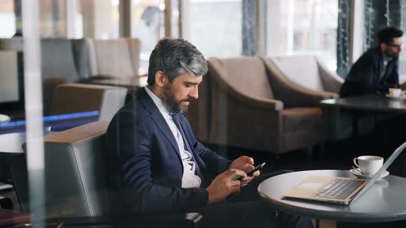 Successful Manager Using Smartphone During Lunch Break in Modern Cafe