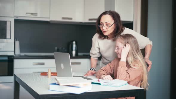 A Kind Grandmother in Eyeglasses Helping Her Granddaughter with Her Homework