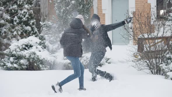 Wide Shot of Cheerful African American Laughing Father and Daughter Fighting Snowballs on Winter