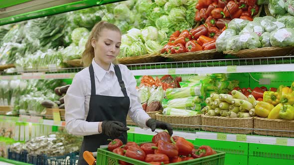 Female Puts Red Pepper on a Shelf in an Organic Store Young Woman Replenishes Products on the