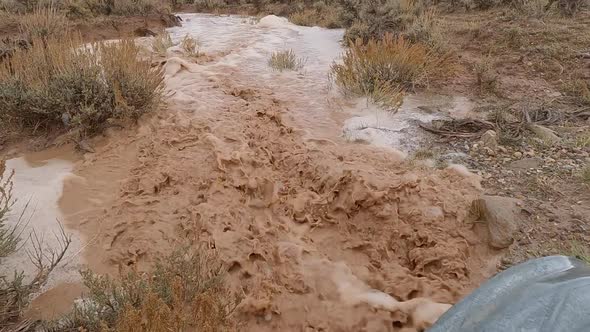 Slow motion of muddy water flowing through the desert following storm