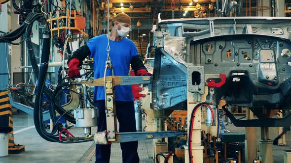 Car Manufacturing Worker Using a Welding Machine at a Car Factory