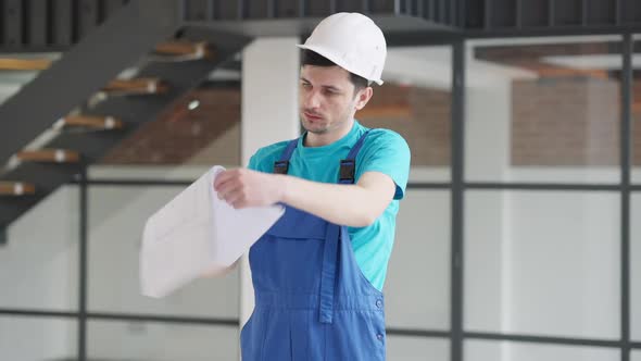 Middle Shot Portrait of Busy Concentrated Young Builder Checking Project Documentation and