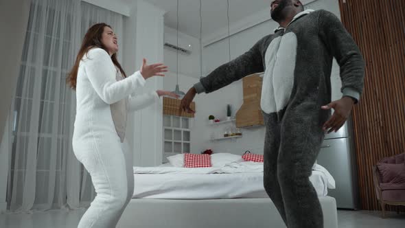 Joyful Multiracial Couple Dancing in Funny Pajamas