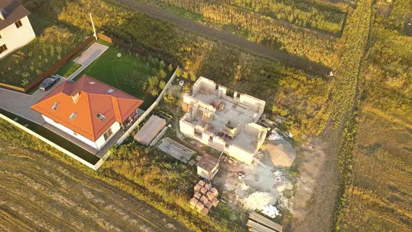 Top Down Aerial View of Two Private Houses One Under Construction with Wooden Roofing Frame and