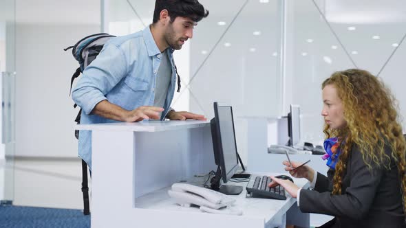 Caucasian male traveler handing passport to airline staff at check in counter in airport terminal