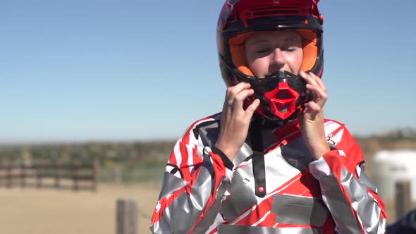 A young woman bmx rider putting on helmet.