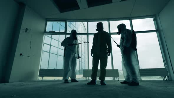 Male Disinfectors Clean Each Other Spraying Antiseptics