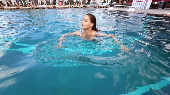 Young Woman Swims in the Pool