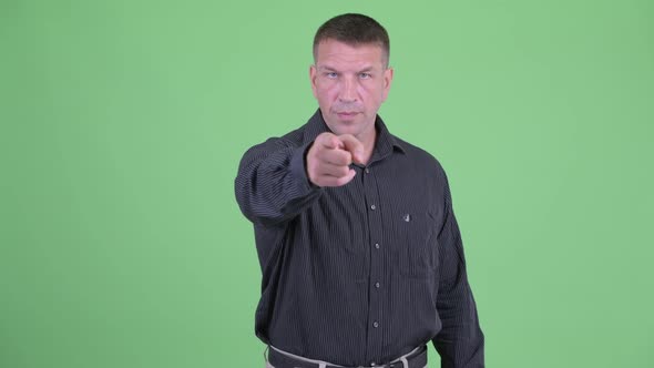 Serious Macho Mature Businessman Pointing at Camera