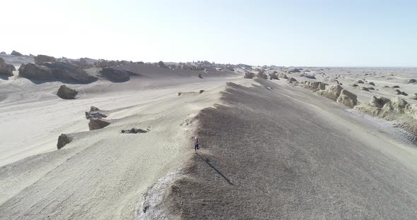 Aerial footage of woman trail runner cross country running  on sand desert dunes