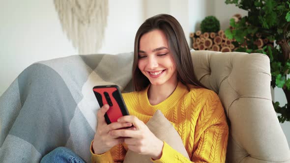 Woman Smiling Hold Smartphone Watching Social Media Stories Video Sit on Sofa