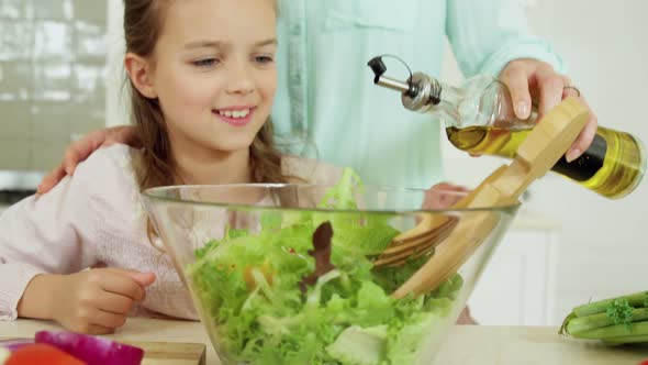 Mother assisting daughter in preparing salad