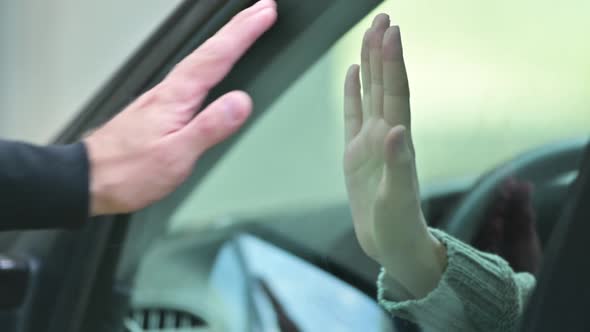 Farewell of two people. Man and the woman put their hands on the glass of car