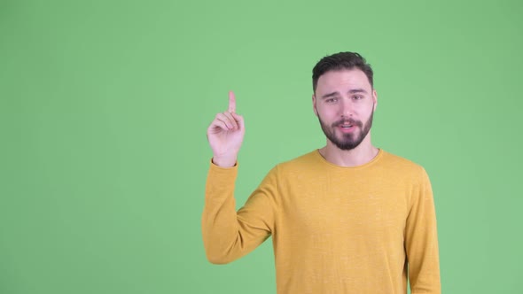 Happy Young Handsome Bearded Man Talking and Pointing Up