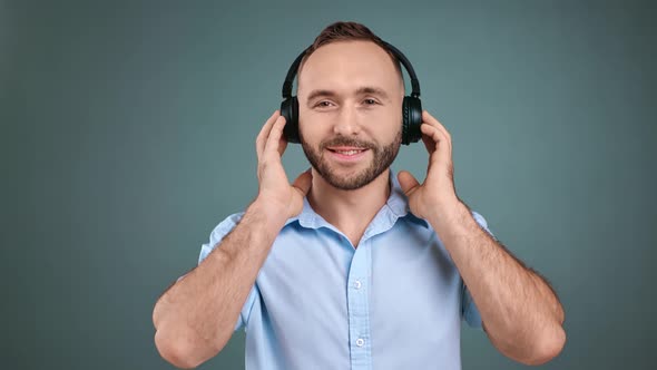 Portrait of Man Listening Music in Headphones Isolated on Gray Studio